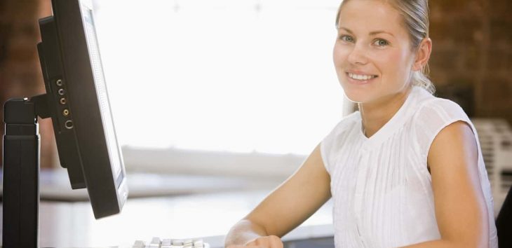 Businesswoman sitting in office with computer smiling